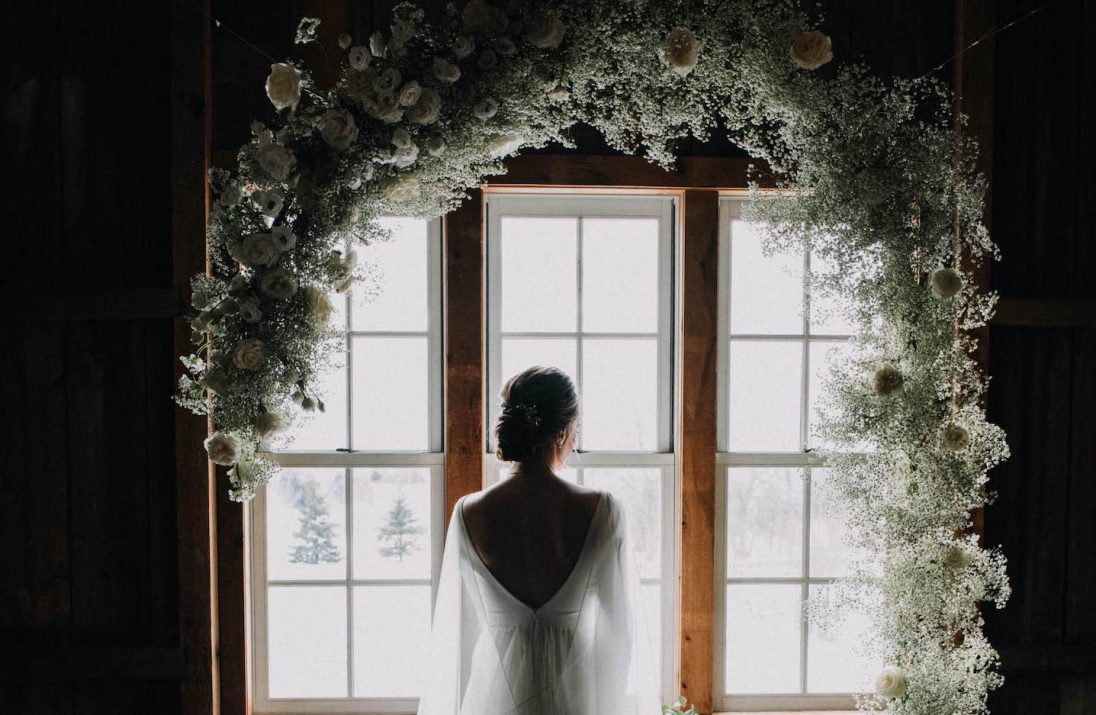 A bride facing a window and looking outside